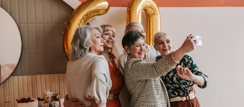 Uśmiechnięta grupa kobiet na przyjęciu robiąca sobie wspólne selfie.