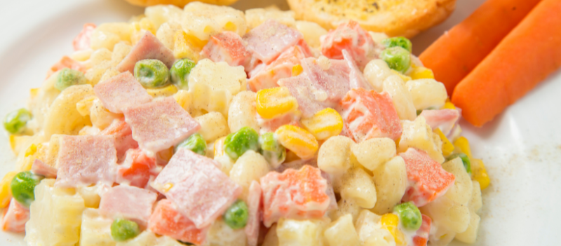 Tradycyjna sałatka jarzynowa w misce, pełna drobno pokrojonych warzyw z majonezem, podawana na świąteczny stół.