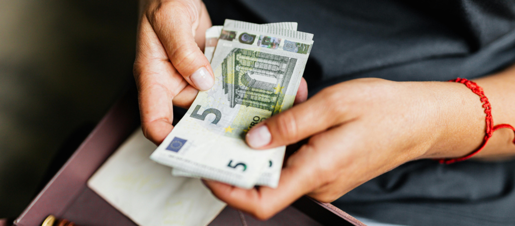 podwyżka dla opiekunki - ręce trzymające banknoty w euro